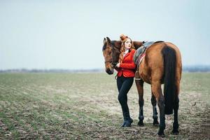 jockey pelirroja con un cárdigan rojo y botas altas negras con un caballo foto