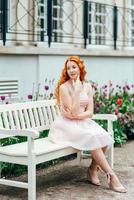 Red-haired young girl walking in a park between trees and architectural objects photo