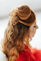 Chica joven con el pelo rojo con un vestido rojo brillante en una habitación luminosa foto