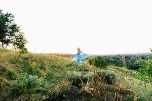 Blonde girl with loose hair in a light blue dress and a guy in the light of sunset photo