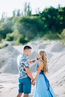 Blonde girl in a light blue dress and a guy in a light shirt in a granite quarry photo