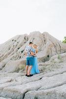 chica rubia con un vestido azul claro y un chico con una camisa ligera en una cantera de granito foto