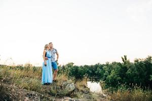 Blonde girl with loose hair in a light blue dress and a guy in the light of sunset photo