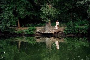 un chico y una chica caminan por las orillas de un río salvaje cubierto de maleza foto