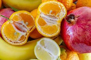 Arreglo de frutas variadas de plátanos, granada, rodajas de limón y rodajas de mandarina foto