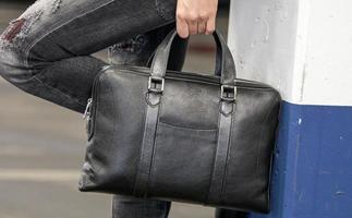Cropped image of a stylish woman holding a big black leather bag