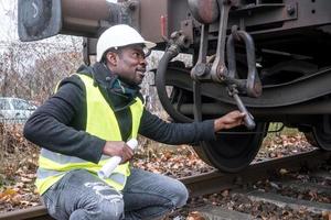 Mecánico afroamericano que controla e inspecciona el tren de engranajes foto