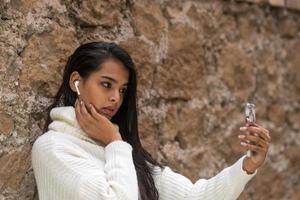 Gorgeous brunette woman with long hair takes self portraits with her smartphone photo