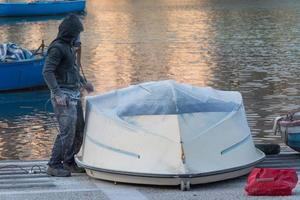 Boatman in mask polishing the hull of a boat with a grinder machine photo