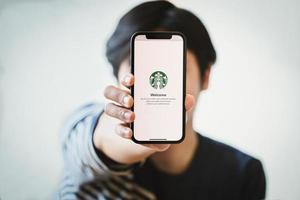 Chiang Mai, Tailandia, 23 de enero de 2021: persona que sostiene un teléfono con la aplicación Starbucks. foto