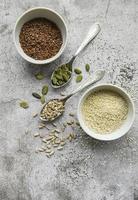 Mix of different seeds for a healthy salad, bowls on a gray concrete background photo