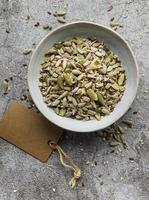 Mix of different seeds for a healthy salad, bowl on a gray concrete background photo