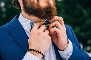 El novio con un traje azul en los Cárpatos de las montañas foto