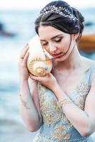 bride with a big shell on the beach photo