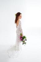 joyful girl bride in a white knitted dress posing with a bouquet of flowers photo