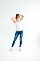 Chica alegre en una camiseta blanca y jeans azul oscuro en el estudio sobre un fondo blanco. foto