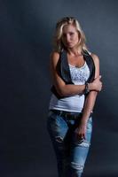 young blonde girl in jeans clothes on a dark background photo