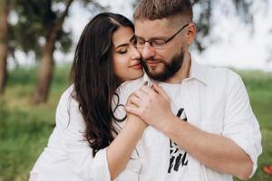 Pareja joven enamorada de un chico con barba y una chica de cabello oscuro con ropa clara foto