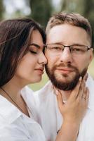 young couple in love a guy with a beard and a girl with dark hair in light clothes photo