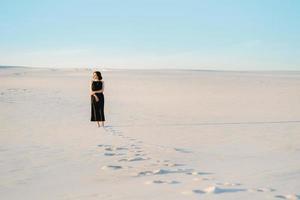 girl in a black dress stands in the middle of the desert photo