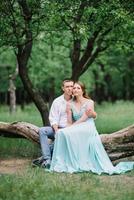 happy guy in a white shirt and a girl in a turquoise dress are walking in the forest park photo