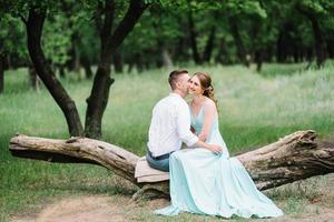 happy guy in a white shirt and a girl in a turquoise dress are walking in the forest park photo