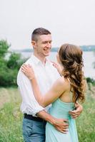 happy guy in a white shirt and a girl in a turquoise dress are walking in the forest park photo