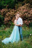 happy guy in a white shirt and a girl in a turquoise dress are walking in the forest park photo