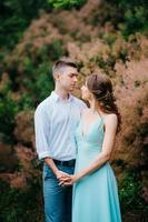 happy guy in a white shirt and a girl in a turquoise dress are walking in the forest park photo