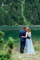 pareja joven en un paseo cerca del lago rodeado por las montañas
