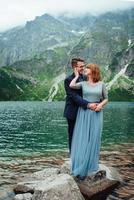 young couple on a walk near the lake surrounded by the mountains photo