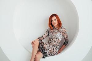 Chica modelo de pelo rojo sobre un fondo de círculo blanco
