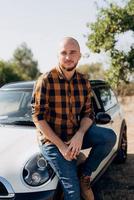 Guy in a plaid shirt next to a white car photo