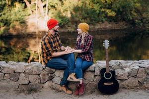 Un chico con un sombrero brillante toca la guitarra con una chica sobre un fondo de rocas de granito foto