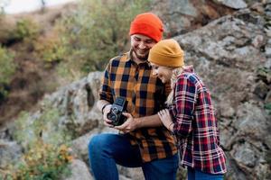 Bald guy with a beard and a blonde girl in bright hats are taking pictures with an old camera photo