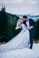 groom in a blue suit and bride in white in the mountains Carpathians photo