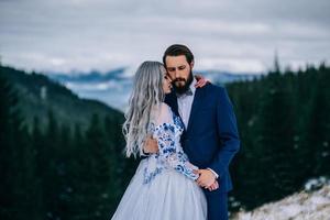 groom in a blue suit and bride in white in the mountains Carpathians photo