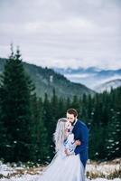 groom in a blue suit and bride in white in the mountains Carpathians photo