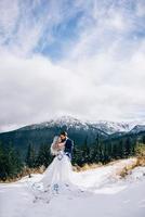 El novio en un traje azul y la novia en blanco en las montañas de los Cárpatos. foto