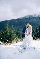 groom in a blue suit and bride in white in the mountains Carpathians photo