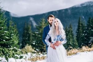 groom in a blue suit and bride in white in the mountains Carpathians photo