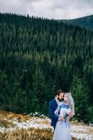 groom in a blue suit and bride in white in the mountains Carpathians photo