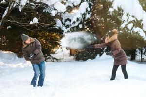 boy and girl outdoors on a winter walk playing snowballs photo