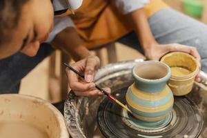 Hands with brush and clay pot photo