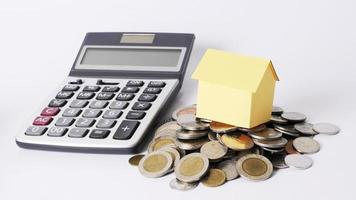 Close up for yellow house and coins stack and Calculator photo