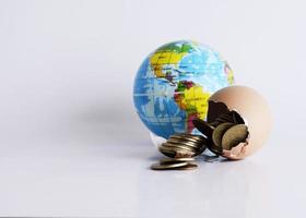 Broken egg with money coins and earth ball for Finance concept photo
