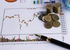 Fountain pen and coins stack on stock index chart for finance concept photo
