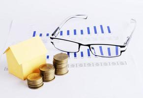 House paper and coins and Eyeglass on chart for Loans money concept photo