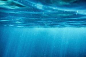 Ondulación de la superficie del océano azul submarino con rayos de sol en el mar tropical foto