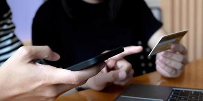 Selective focus of positive man holding smartphone while using  credit card near woman photo